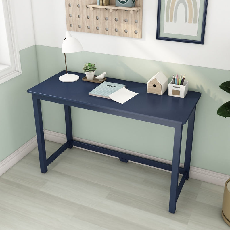 Modern blue desk in minimalist home office setup with lamp, plants, and stationery.