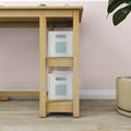 Under-desk wooden shelving with two white storage boxes and a potted plant against a pastel pink wall, modern home office storage solution