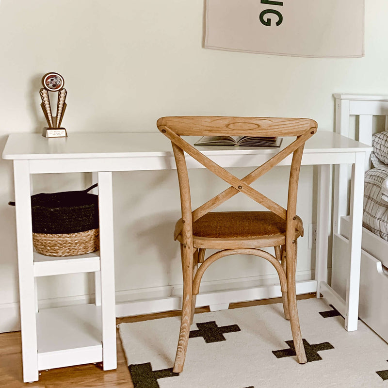 Wooden chair and white desk in a minimalist home office with a decorative trophy and book.