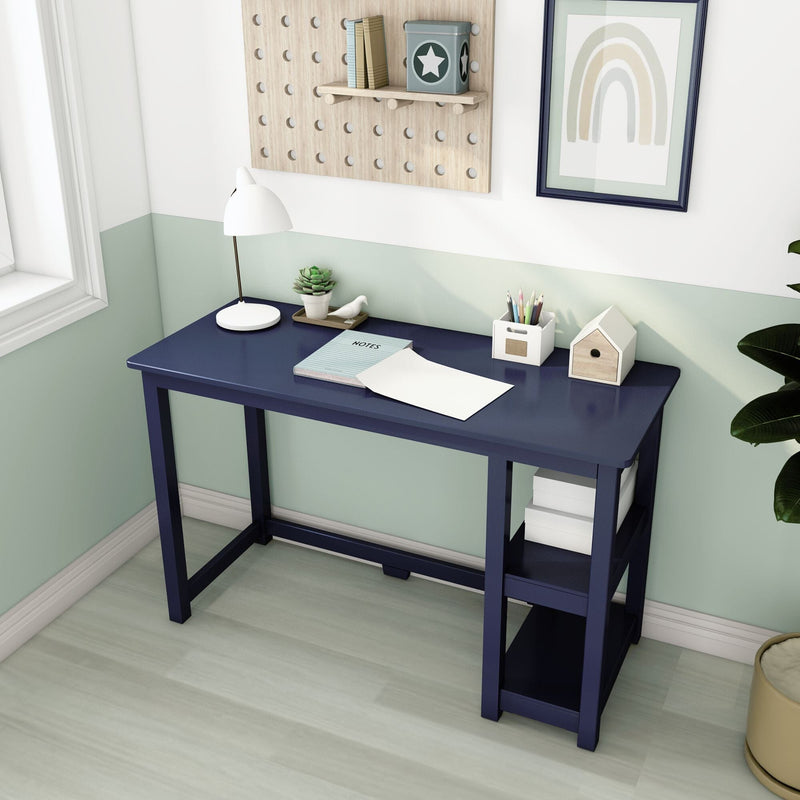 Navy blue wooden writing desk with open shelves, white desk lamp, notebook and pencil holder in a pastel green modern home office nook