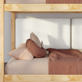 Close-up of natural wood bunk bed with textured white headboard, beige gingham pillow, round rust-brown cushion and terracotta duvet in a Scandinavian children's bedroom