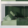Top-down view of modern green bedding: dark green duvet, gingham pillow, round green cushions and padded green headboard panels in a white bed frame