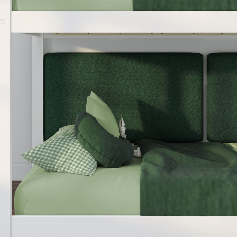 Top-down view of modern green bedding: dark green duvet, gingham pillow, round green cushions and padded green headboard panels in a white bed frame