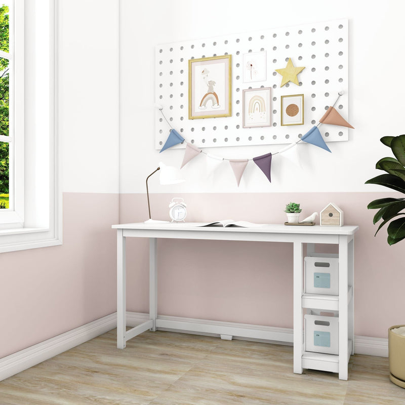 White kids desk in pastel pink nursery with pegboard wall organizer, framed rainbow art and bunting, desk lamp, storage bins and plant by a sunny window