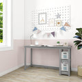 Kids study desk in a pastel nursery with pegboard wall decor, framed rainbow prints and bunting flags, white desk lamp, under-desk storage bins and potted plant by window