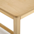 Close-up of wooden table corner with rounded edge and natural light finish, solid leg and minimalist modern design