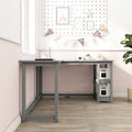 Modern gray L-shaped kids desk in pastel pink nursery study corner with storage shelves, lamp, decorative pennant banner and framed wall art on wood floor