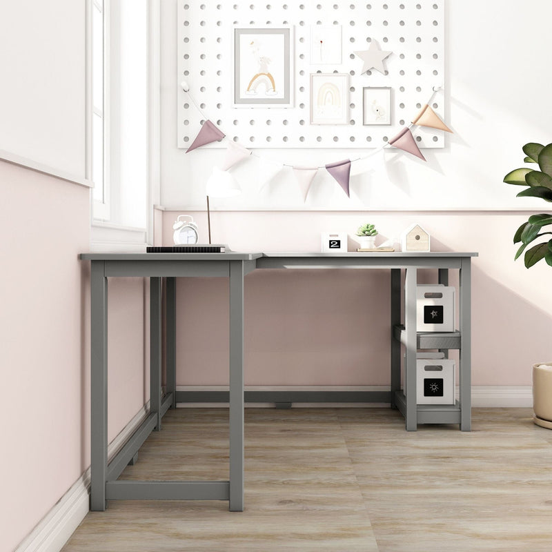 Modern gray L-shaped kids desk in pastel pink nursery study corner with storage shelves, lamp, decorative pennant banner and framed wall art on wood floor