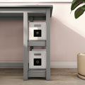 Under-desk storage solution — gray desk with two white fabric storage cubes on shelves against a blush pink wall and hardwood floor