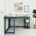 L-shaped navy blue wooden corner desk with open shelving, white desk lamp, storage boxes, pegboard organizer and potted plant in a modern pastel home office