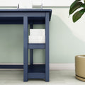 Modern navy blue desk with built-in shelf holding stacked white storage boxes against a mint green wall and potted plant