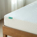 Mattress with a brand label on a wooden bed frame against a neutral background