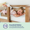 Bunk bed guardrail safety — smiling child lying on mattress behind low-profile wooden guardrail, snug fall-prevention design for kids