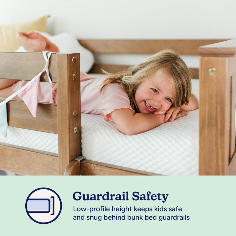 Bunk bed guardrail safety — smiling child lying on mattress behind low-profile wooden guardrail, snug fall-prevention design for kids