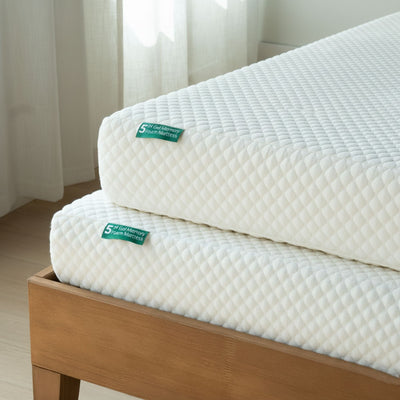 Stacked white 5-inch gel memory foam mattresses with quilted cover on a wooden bed frame in a bright minimalist bedroom