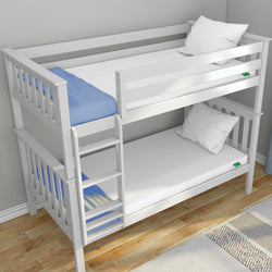 White wooden twin bunk bed with ladder and guardrails, two white mattresses and pillows, blue blanket, hardwood floor and rug in a modern kids' bedroom