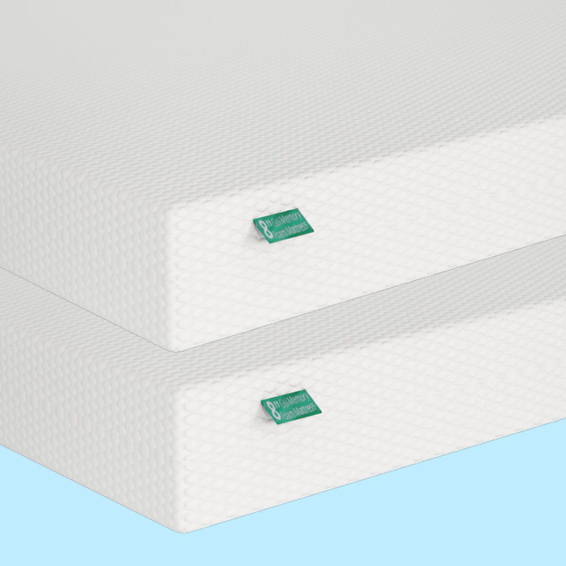 Tall layers of high-density memory foam mattresses with textured white covers and green labels.