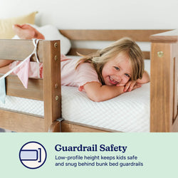 Child smiling on a wooden bunk bed with safety guardrails, highlighting secure low-profile design.