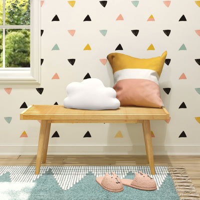 Cozy nursery decor with cloud pillow, colorful geometric wallpaper, and cute animal slippers on wooden bench.