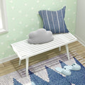 Cozy corner with white bench, cloud pillow, striped cushion, and blue slippers on a decorative rug.