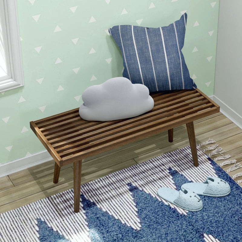 Cozy entryway with modern wooden bench, striped cushion, cloud-shaped pillow, and blue slippers.