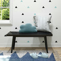 Decorative bench with cloud cushion and pillow in modern room with geometric wall decals and cute animal slippers.