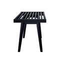 Modern black wooden slat bench with four sturdy legs on white background.