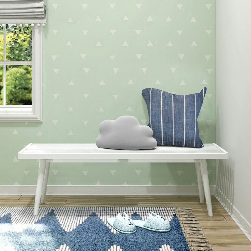 Cozy reading nook with cloud pillow on a white bench, featuring a striped cushion, patterned rug, and soft slippers next to a window.