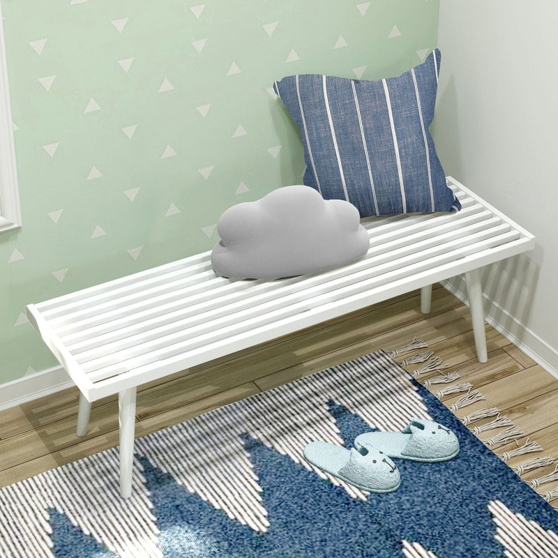 Modern white slatted bench with blue striped pillow and cloud-shaped cushion on wooden floor.