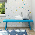 Colorful kids' room with blue bench, cloud cushion, and modern geometric decor.