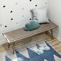 Modern wooden slatted bench with decorative pillows and cozy slippers in a stylishly decorated room.