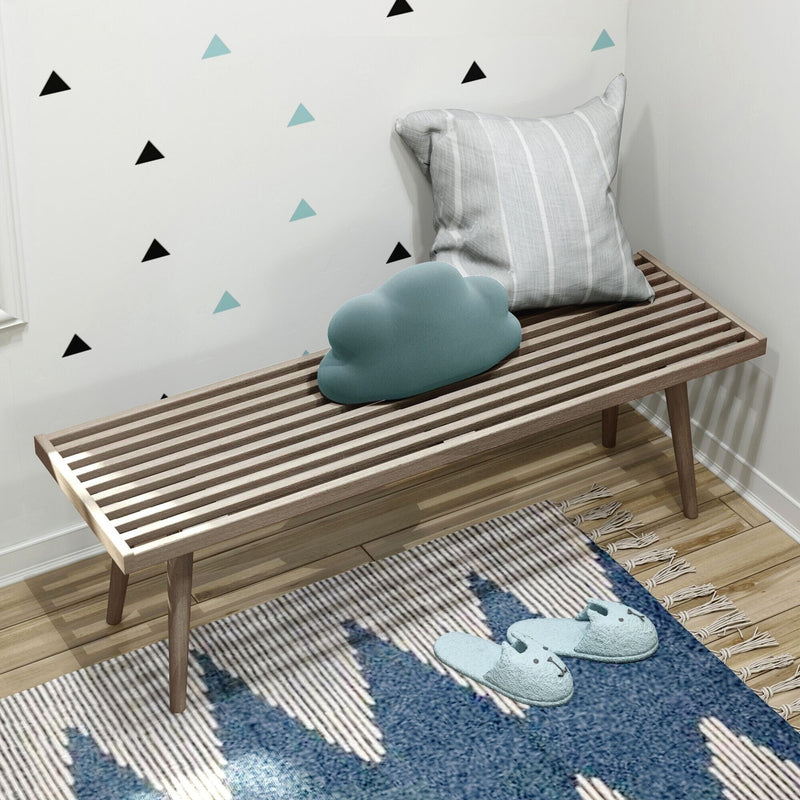 Modern wooden slatted bench with decorative pillows and cozy slippers in a stylishly decorated room.