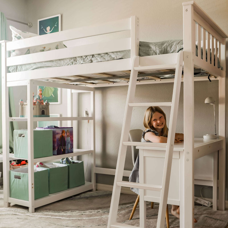 Child smiling at desk under white loft bed in organized playroom with storage shelves.