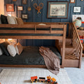 Wooden bunk bed in children's bedroom with navy paneled accent wall, cozy dark-green bedding, vintage framed art, globe and wooden toy train
