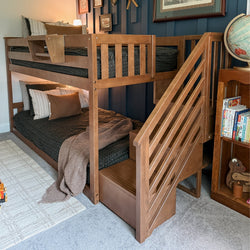 Solid wood bunk bed with built-in staircase and storage in a cozy kids' bedroom with navy accent wall, globe and bookshelf