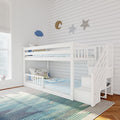 White wooden twin-over-twin bunk bed with built-in staircase storage in a bright kids' bedroom featuring blue-striped bedding, a striped area rug, and star-and-moon wall decor.