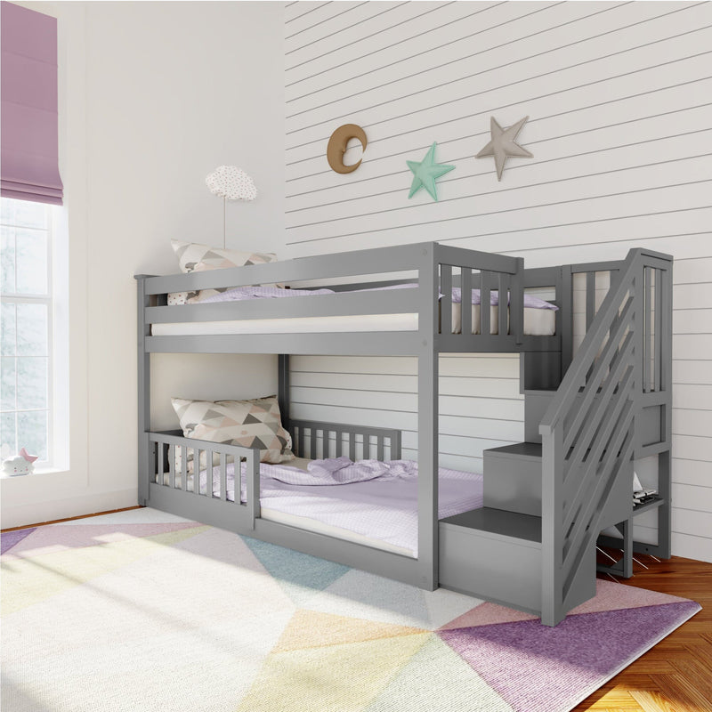 Gray bunk bed with storage stairs in a modern children's room featuring a pastel geometric rug and decorative wall accents.