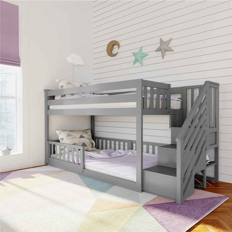 Gray wooden bunk bed with staircase in a modern kids' room featuring wall decor and a multicolored geometric rug.