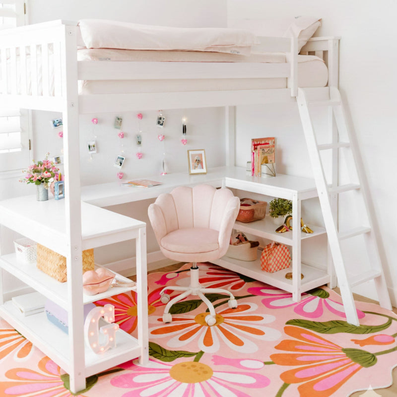 Girls loft bed with built-in white desk and ladder, pink swivel chair and colorful floral area rug in bright kids bedroom workspace