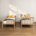 Twin wooden beds in a modern minimalist kids' bedroom with white bedding, yellow accent pillows, natural sunlight casting window shadows on a neutral wall and warm hardwood floors