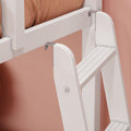 Close-up of white wooden bunk bed ladder with metal hooks attached to loft bed frame against pink wall