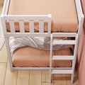 White wooden bunk bed with ladder and peach-colored bedding in a modern kids' bedroom with hardwood floor and pink wall