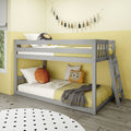 Grey wooden bunk bed in bright yellow kids' bedroom with lion throw pillow, polka dot rug, tassel wall garland and cozy bedding