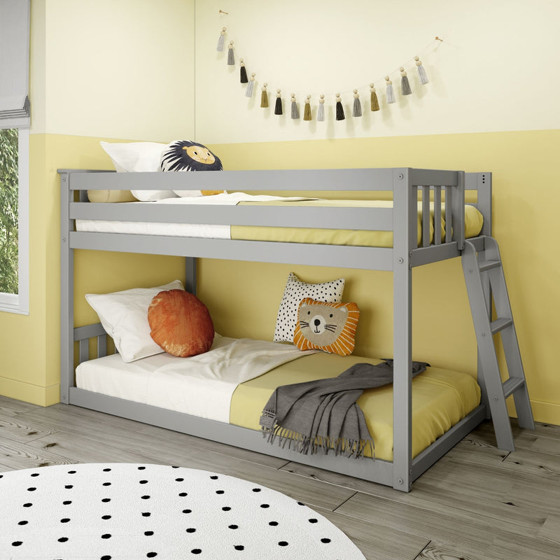 Grey wooden bunk bed in bright yellow kids' bedroom with lion throw pillow, polka dot rug, tassel wall garland and cozy bedding
