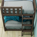 Rustic dark wooden bunk bed with ladder, gray bedding and teal blanket on lower bunk, light wood floor and aqua wall