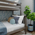 Gray wood twin-over-twin bunk bed with white linens, blue striped and mustard accent pillows, knit round cushion, blue geometric wallpaper and potted fiddle leaf fig plant.