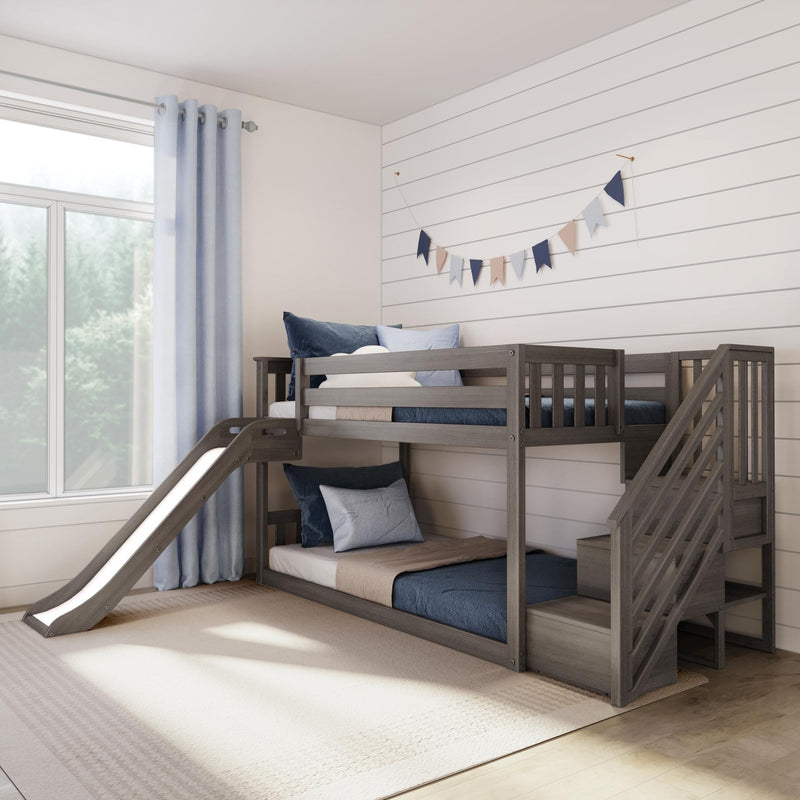 Gray wooden bunk bed with slide in modern kids' bedroom, navy and beige bedding, pennant garland on white shiplap wall and light blue curtains