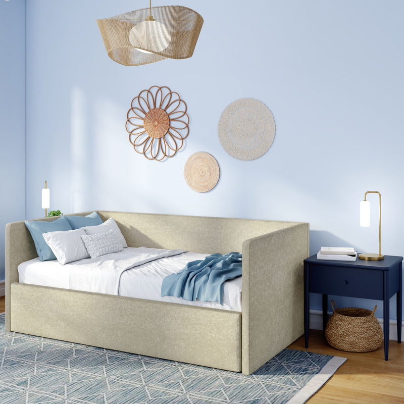 Beige upholstered daybed with blue throw, rattan wall decor, pendant light and navy nightstand in a modern coastal bedroom