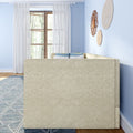 Bright living room with beige sofa back, sheer white curtains over a wooden window, light blue walls, woven rattan wall decor, blue geometric rug, and coordinating blue throw pillows.