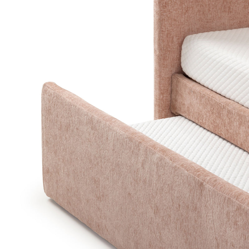 Blush pink upholstered bed frame with textured fabric and white quilted mattress corner, modern platform bed headboard and footboard detail